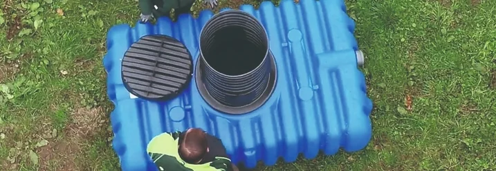 Zwei Personen betrachten eine Zisterne.